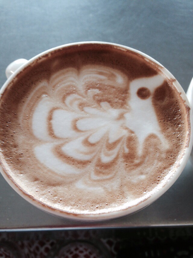 El dibujo de un pavo real con la espuma de la leche en una taza de café